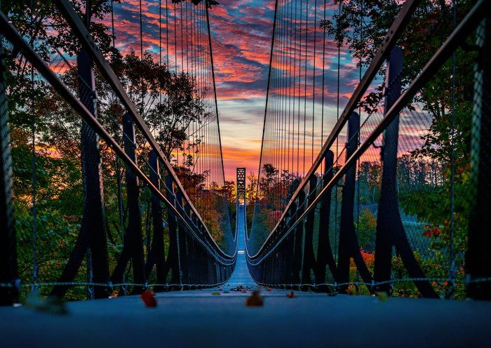 the sun is setting over a suspension bridge