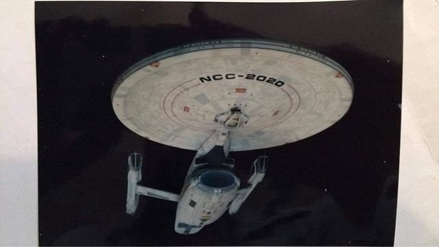 an aerial view of a star trek ship in the air with its landing gear down