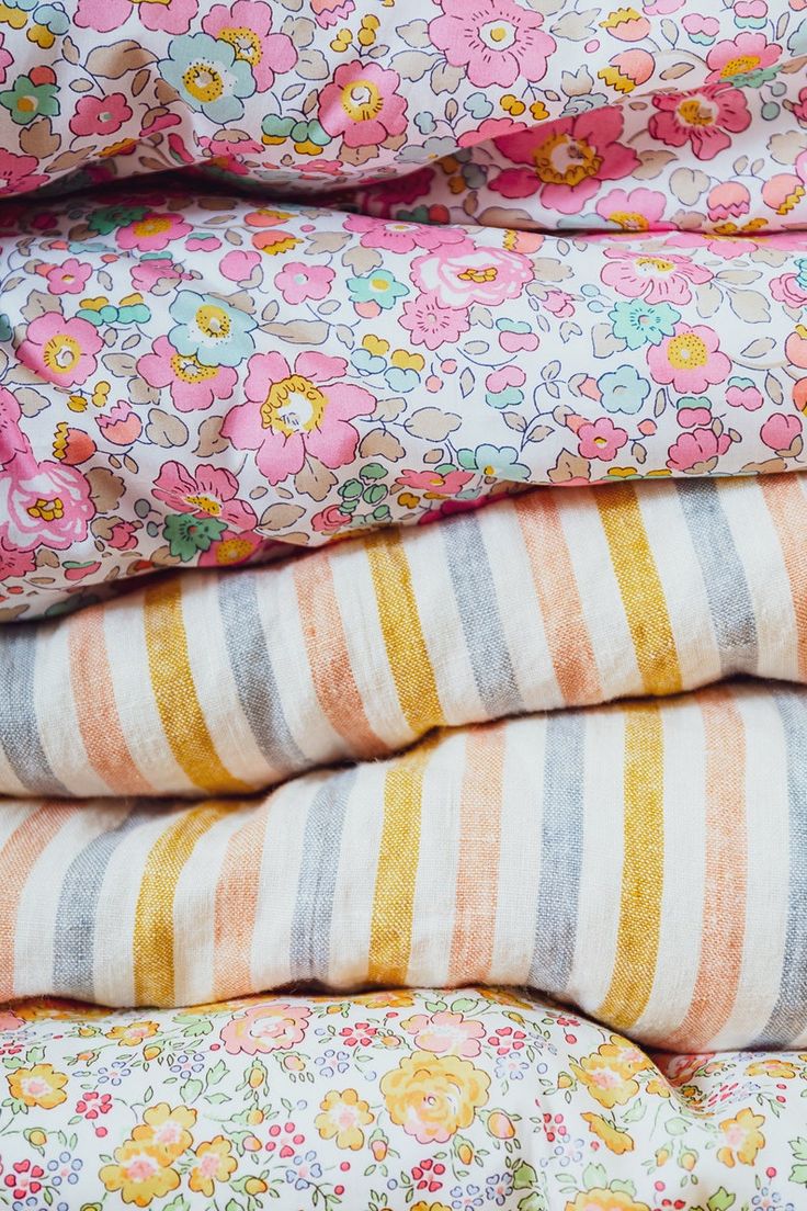 a stack of colorful striped and flowered sheets on top of each other, with flowers all over them