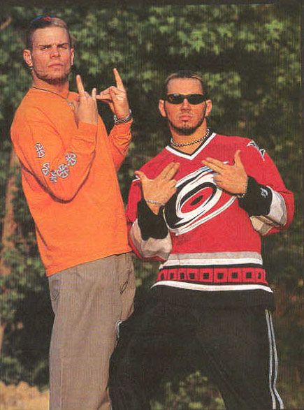two men standing next to each other with their hands in the shape of peace signs