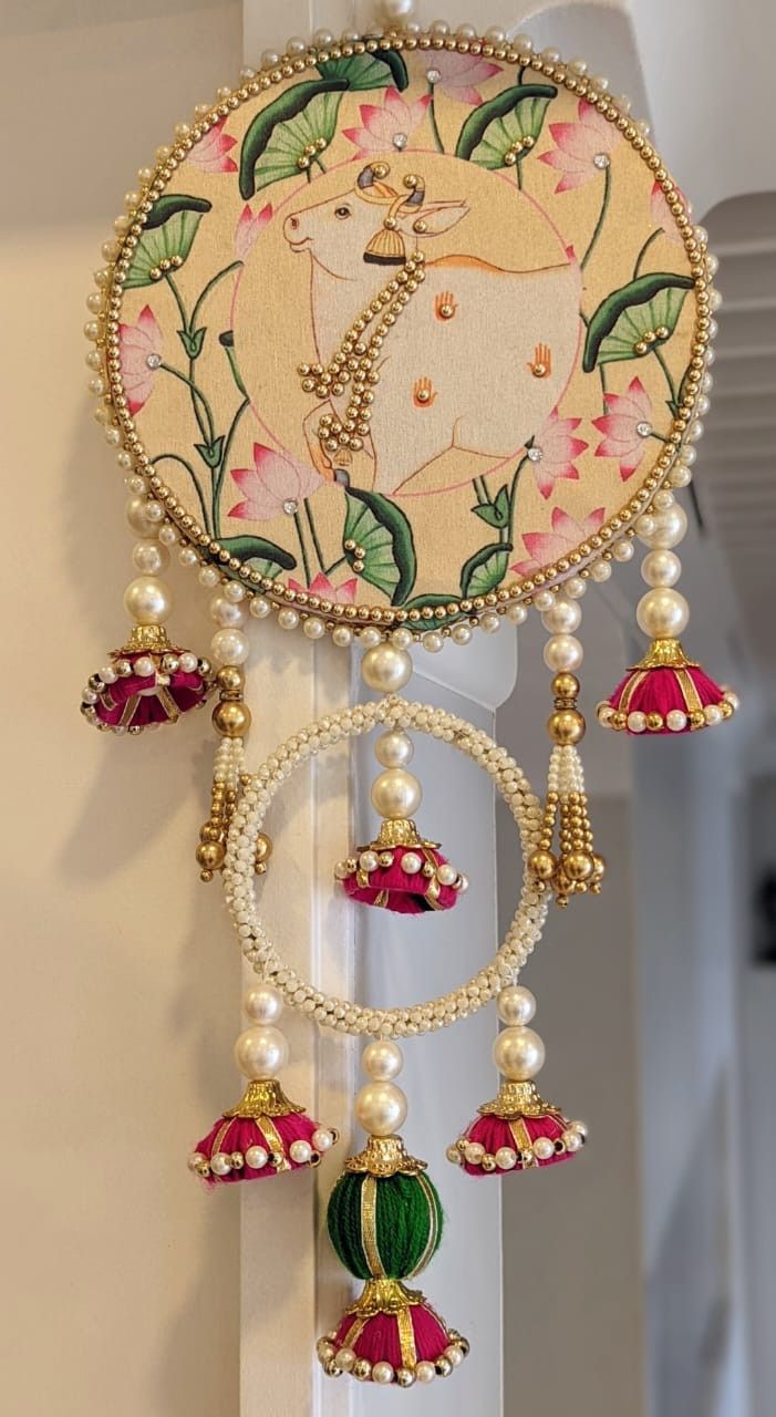 a clock decorated with beads and bells on the wall in a room that has white walls