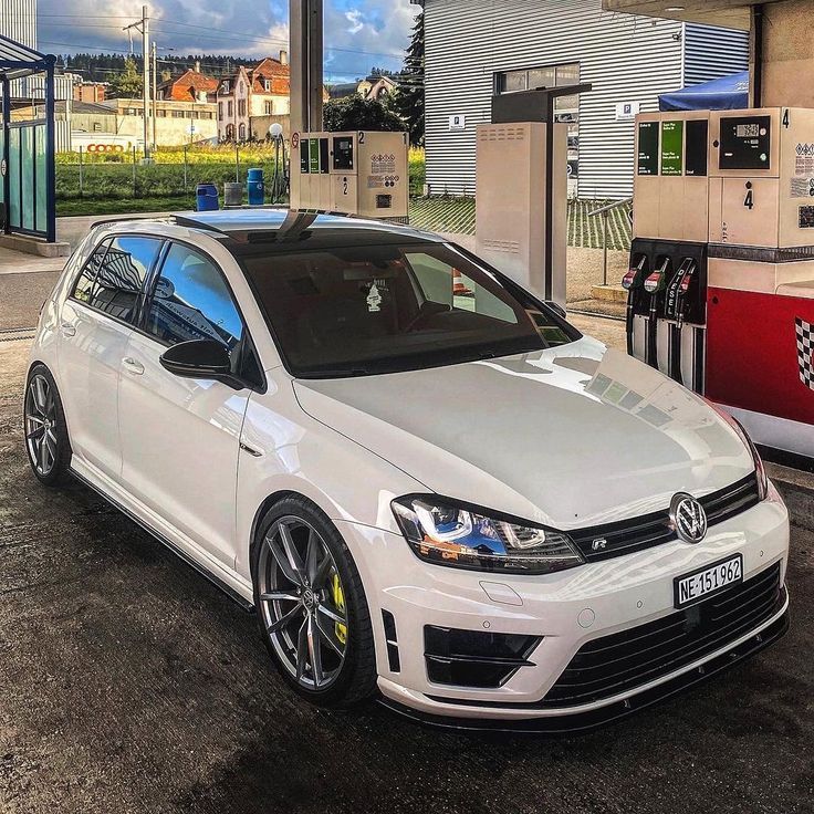 a white car parked in front of a gas station with no one around it,