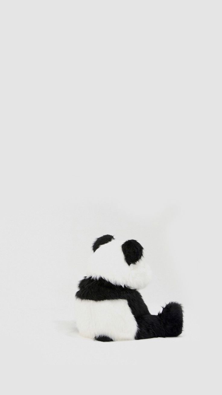 a black and white stuffed panda bear laying down