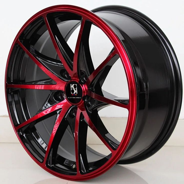 a close up of a wheel on a white surface with red accents and black rims