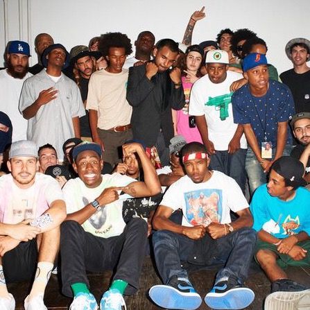 a group of young men sitting next to each other in front of a white wall