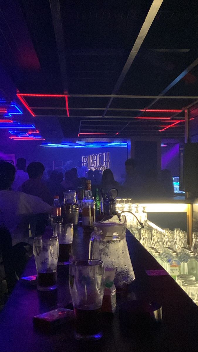 people sitting at a bar with glasses on the counter and bottles in front of them