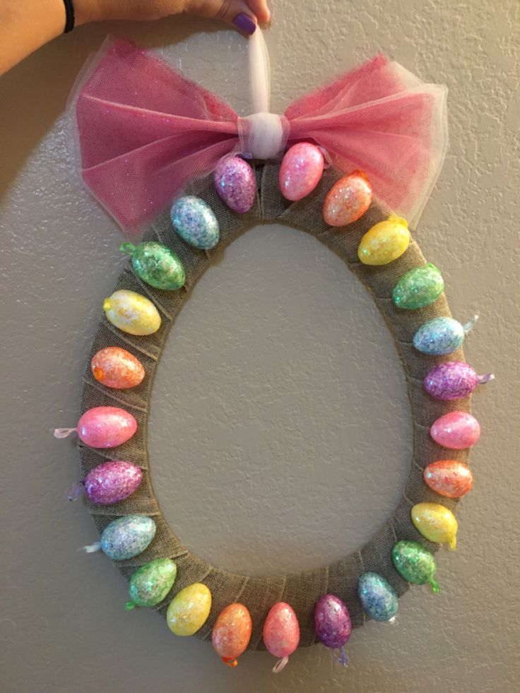 a wreath made out of candy eggs with a pink bow on the front and side