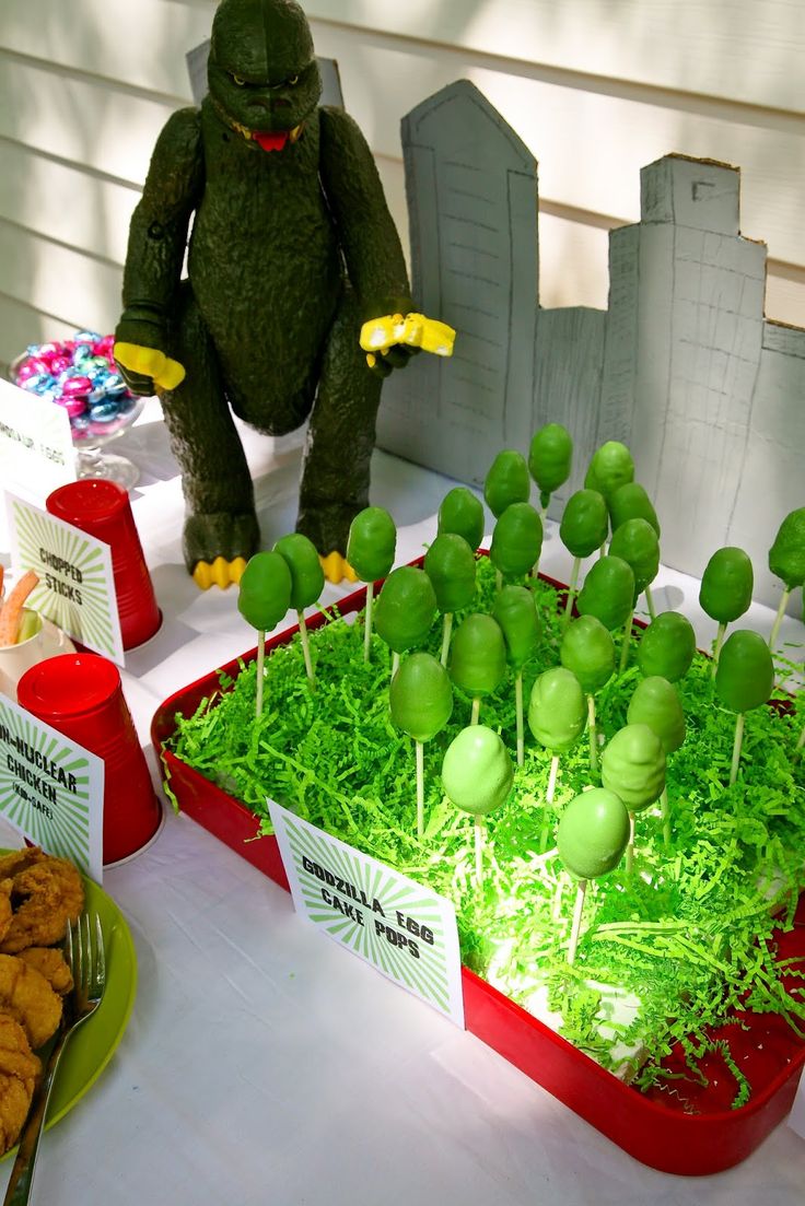 a table topped with lots of food and desserts next to a stuffed animal in the grass