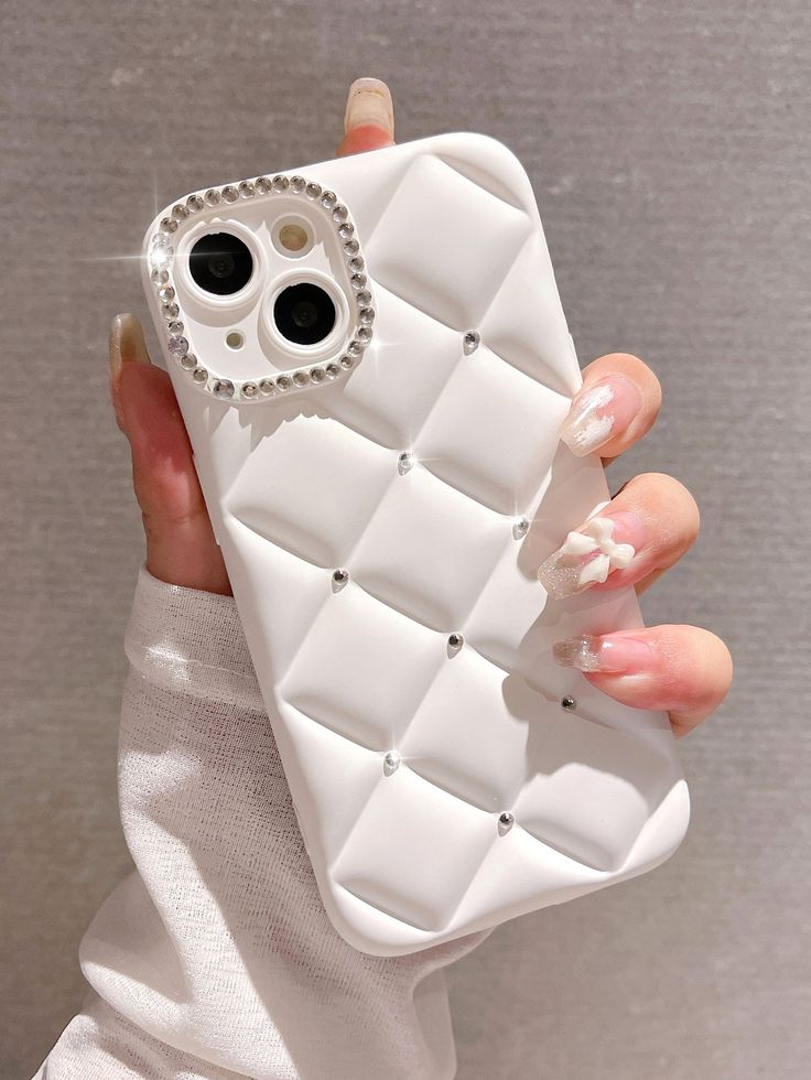 a woman's hand holding a white cell phone case with diamond studs on it