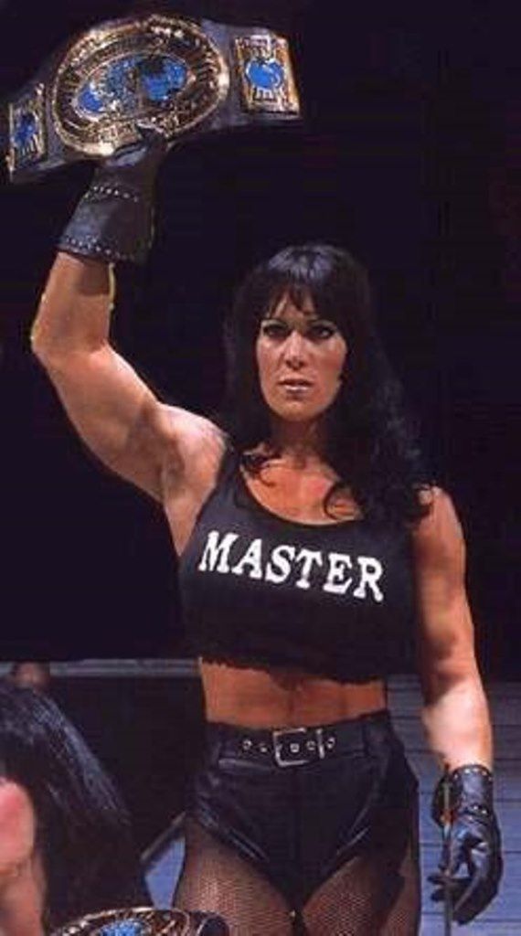 a woman holding up a wrestling belt in the air
