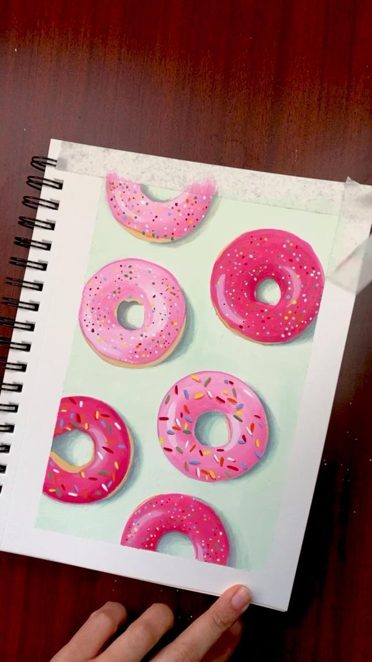 a person holding up a notebook with donuts on it