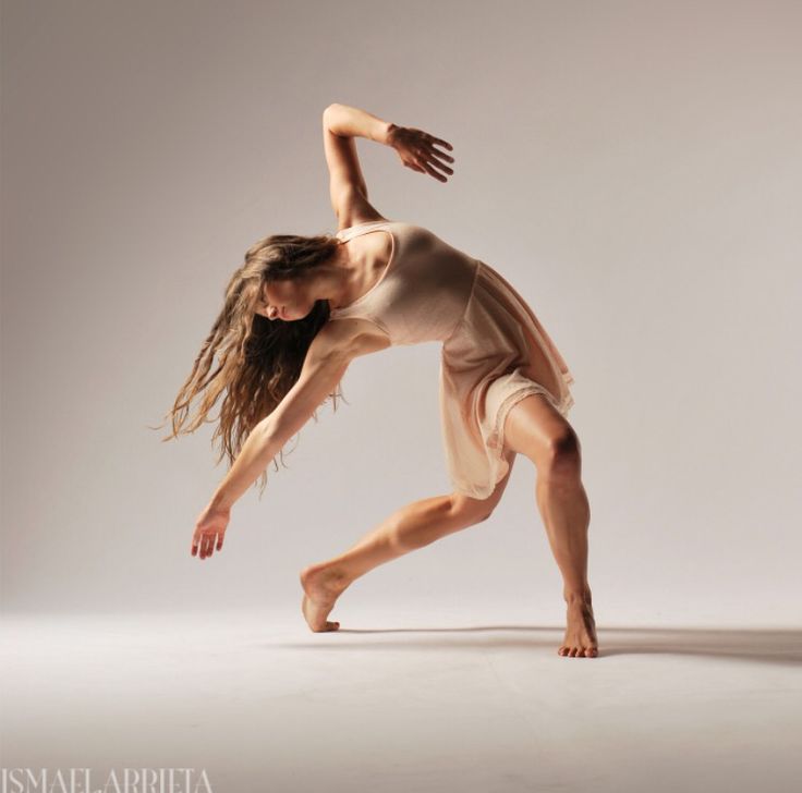 a woman is dancing in the middle of a dance pose with her arms stretched out