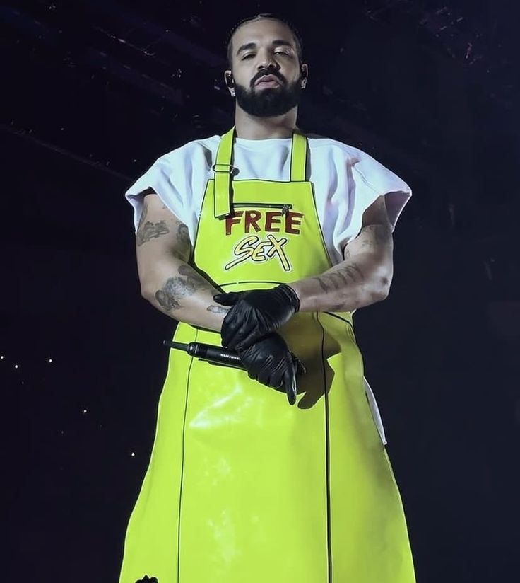 a man in an apron with his arms crossed and one hand on his hip while wearing black gloves