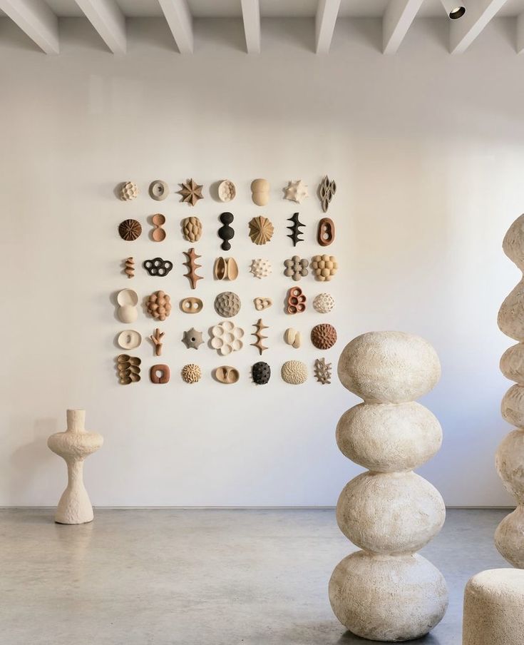 several sculptures are arranged on the wall in front of a white wall with multiple circles