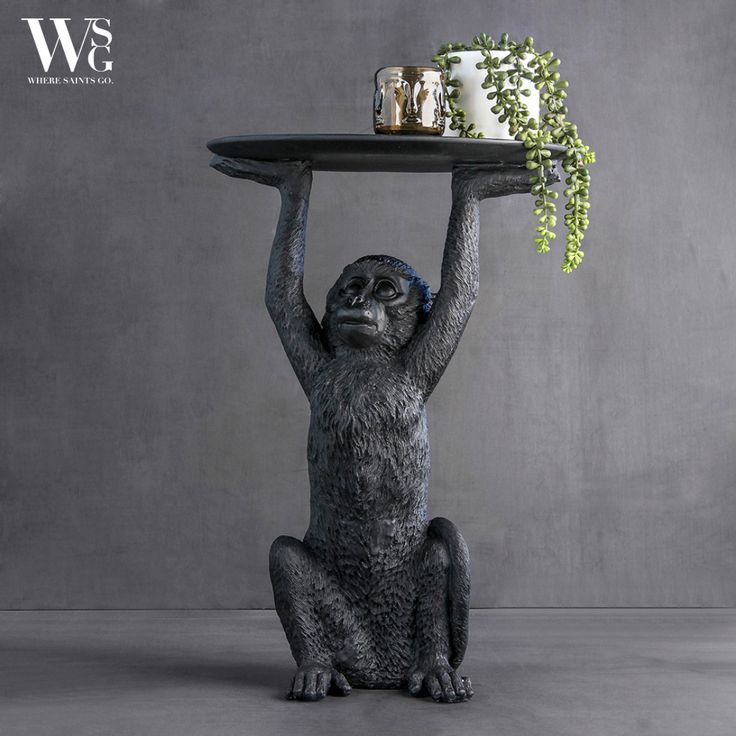 a statue of a monkey holding a tray with plants on it's back legs