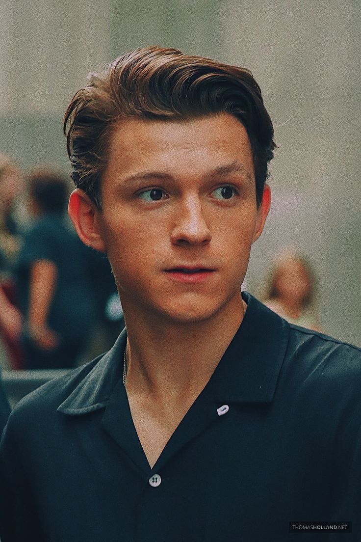 a young man in a black polo shirt looking at the camera with an intense look on his face