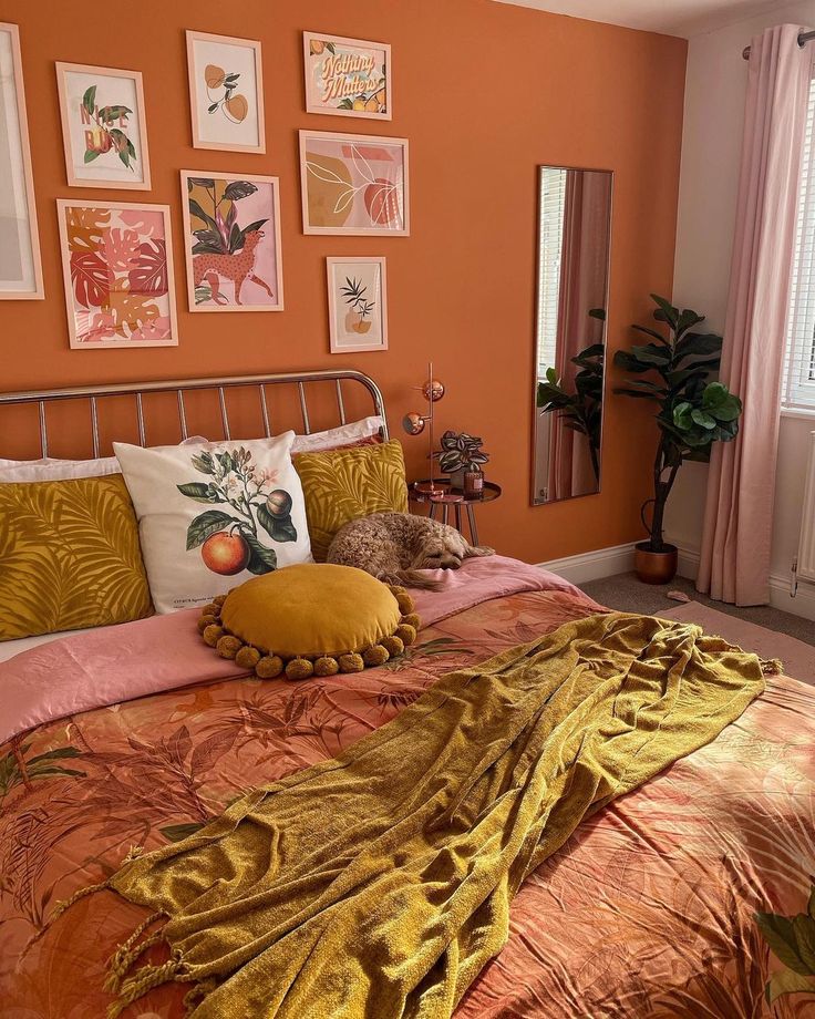 a bedroom with orange walls and pictures on the wall above the bed, along with two stuffed animals