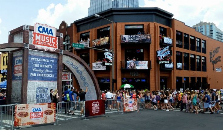 a crowd of people standing in front of a large building with signs on it's sides