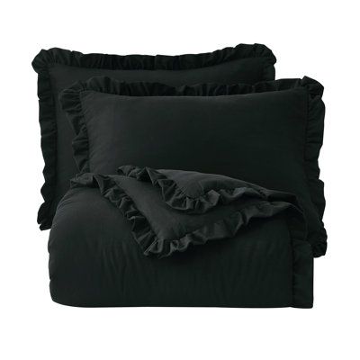 black bedding with ruffles on the bottom and pillow cases, both made from cotton