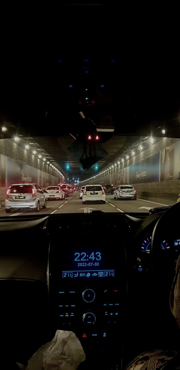 the interior of a car driving through a tunnel at night with lights on and cars in the distance