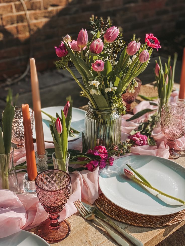 the table is set with pink flowers and candles