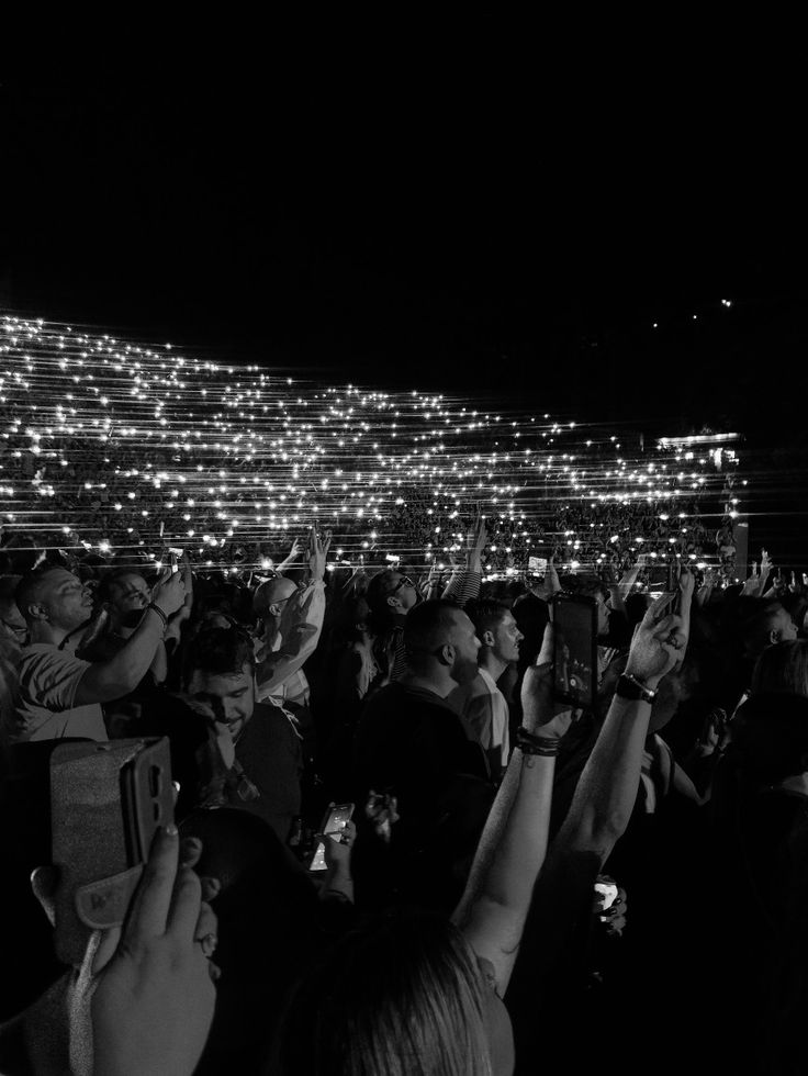 a group of people standing around each other with their cell phones up in the air