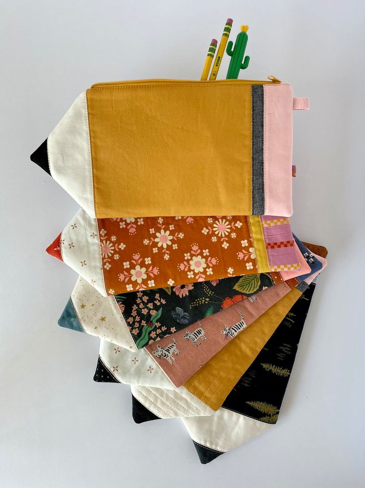 a stack of different colored fabrics on top of each other with pencils sticking out of them