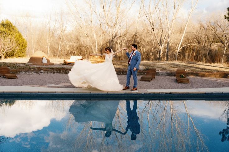 the bride and groom are walking by the pool