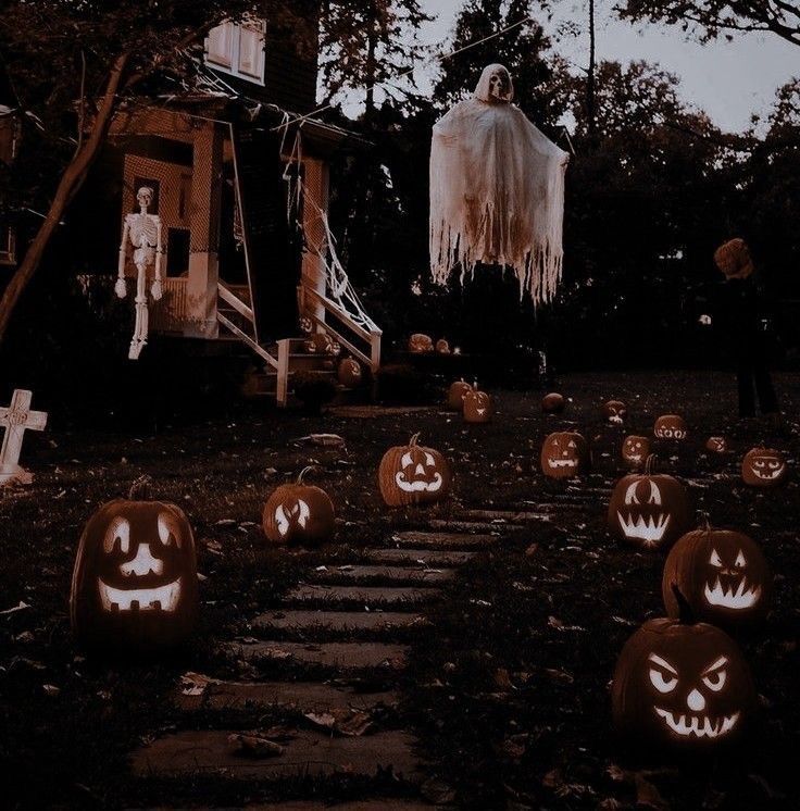 halloween pumpkins with faces carved into them in front of a house decorated for halloween