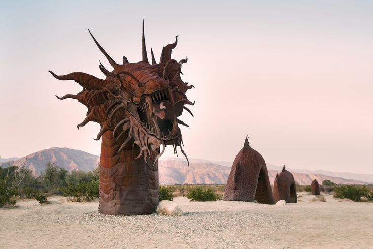 an artistic sculpture in the desert with mountains in the background