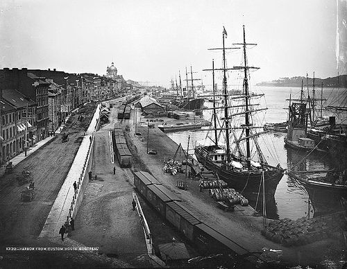 an old black and white photo of a harbor with ships in the water next to buildings