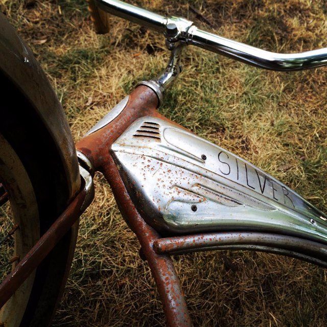 an old rusty bicycle parked in the grass with rust on it's handlebars