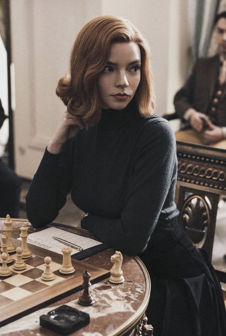 a woman sitting at a table playing chess