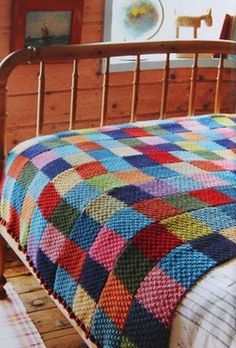 a bed with a colorful quilt on it in a room next to a wooden wall