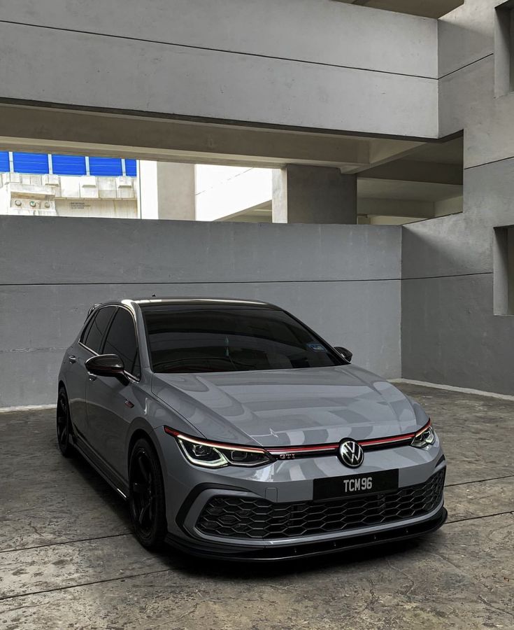 a grey car is parked in front of a building with concrete floors and large windows