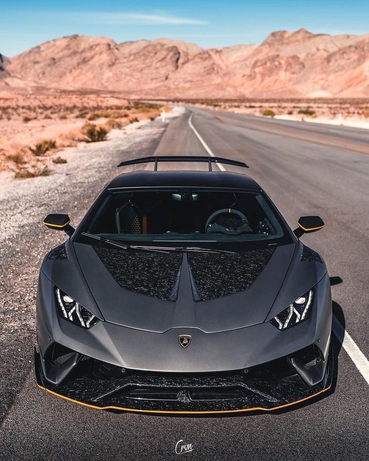 a black sports car is parked on the side of the road with mountains in the background