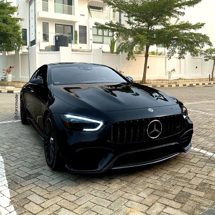 a black sports car parked in front of a white building on a brick parking lot