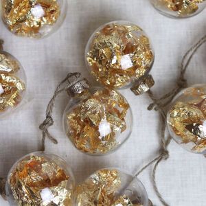 several glass ornaments with gold foil on them sitting on a white cloth covered tablecloth