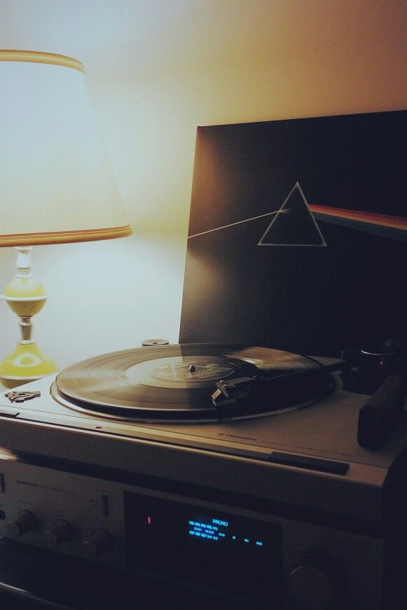 a turntable sitting on top of a table next to a lamp and a record player