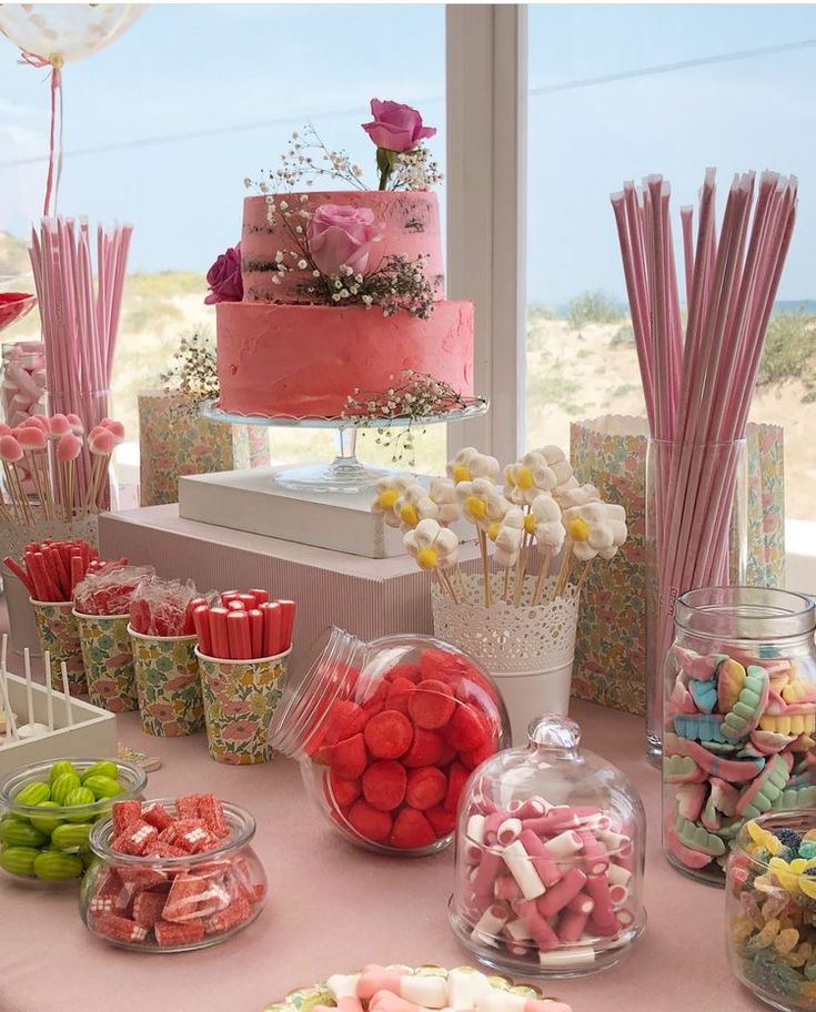 a table topped with lots of candy and candies next to a window filled with flowers