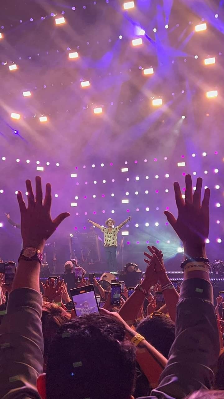 a crowd of people at a concert with their hands in the air and one person on stage