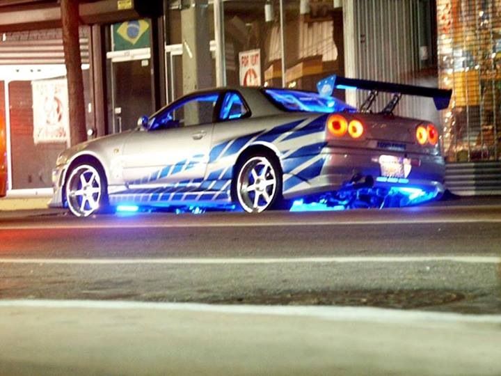 a silver car parked on the side of a street next to a tall building at night