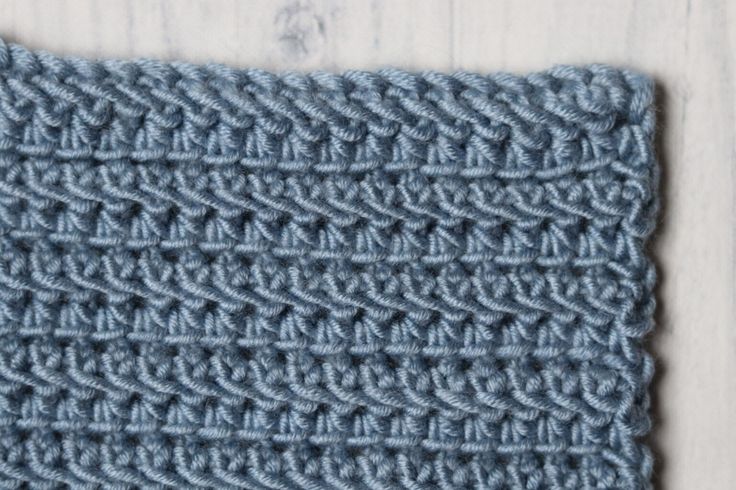 a blue crocheted dishcloth on a wooden surface