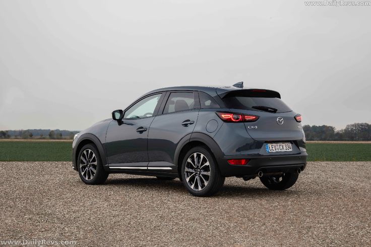 the rear end of a gray mazda cx - 3 parked in a gravel lot