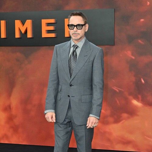 a man in a suit and sunglasses standing on a red carpet