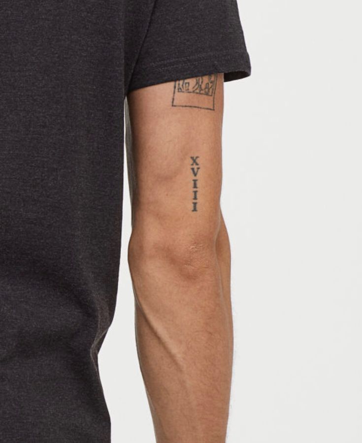 a man with a tattoo on his arm is wearing a black t - shirt and jeans