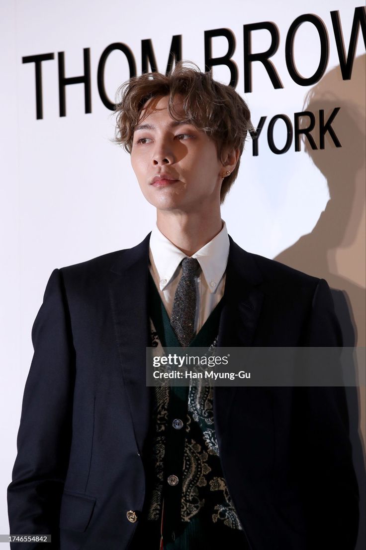 a man wearing a suit and tie standing in front of a wall with words on it