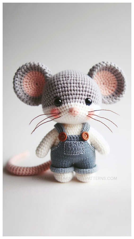 a small crocheted rat with overalls and a button on it's chest