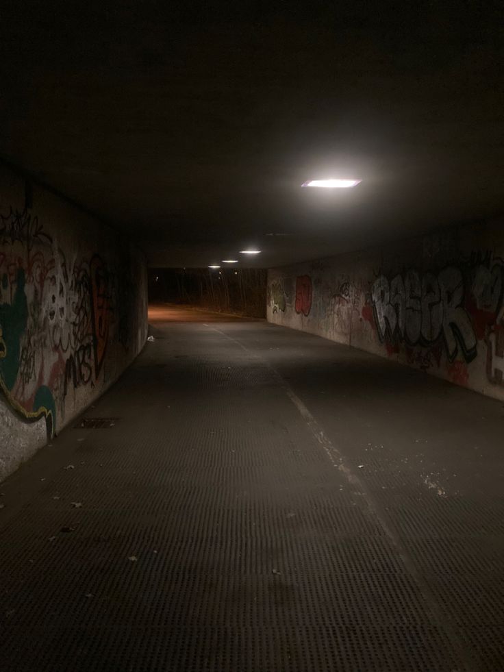 an empty parking garage with graffiti all over the walls and floor, at night time