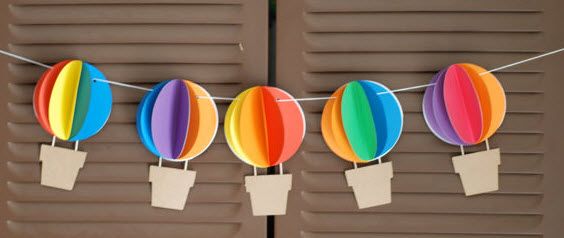 several colorful hot air balloons hanging from clothes pins on a line with paper tags attached to them